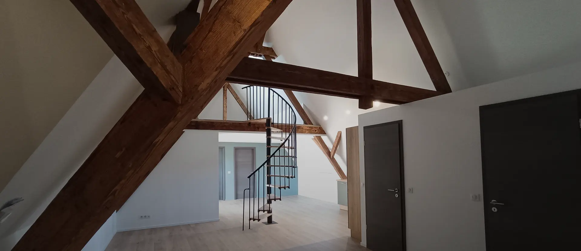 Appartement sous combles rénové, charpente apparente et escalier en colimaçon